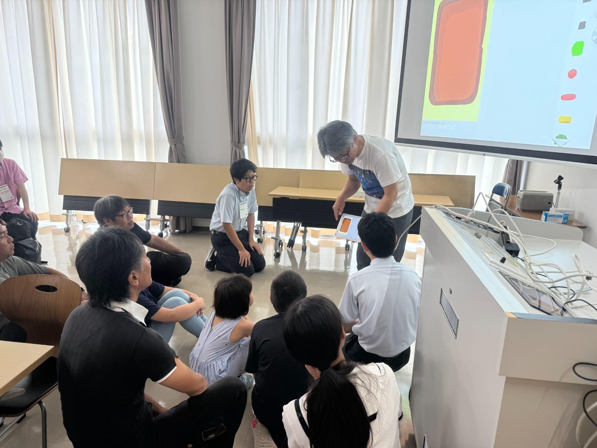 モニターの前で説明を聞く参加者