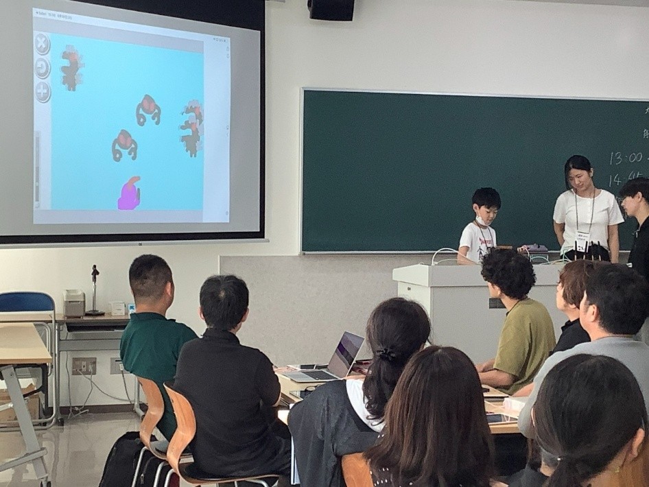 参加者が作った作品をスクリーンに映して発表する様子